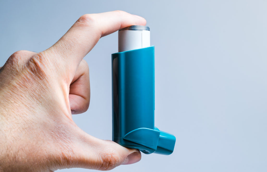 A hand holds a medical inhaler for asthma and lung diseases A hand holds a medical inhaler for asthma and lung diseases