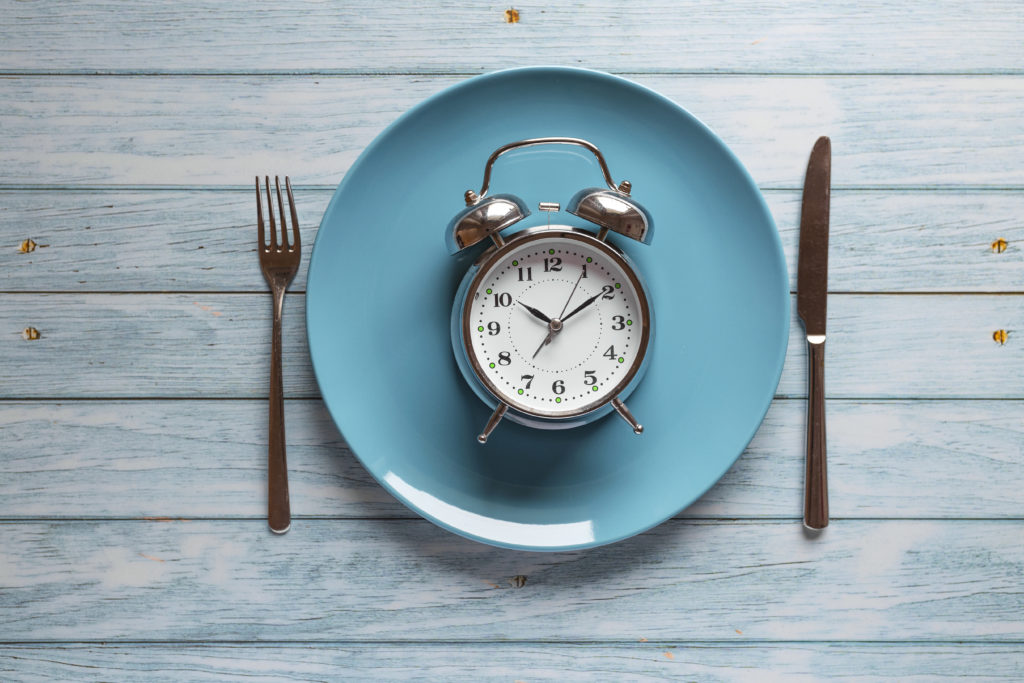 Meal planning for diet concept, Intermittent fasting concept with clock on plate, fork and knife on wooden table, Clock on plate with fork and knife, intermittent fasting, meal plan, weight loss Meal planning for diet concept , Intermittent fasting concept with clock on plate, fork and knife on wooden table, Clock on plate with fork and knife, intermittent fasting, meal plan, weight loss